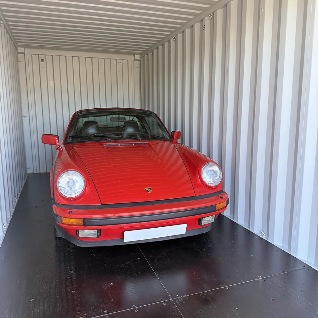 Red classic car inside a shipping container in storage facility in Croydon